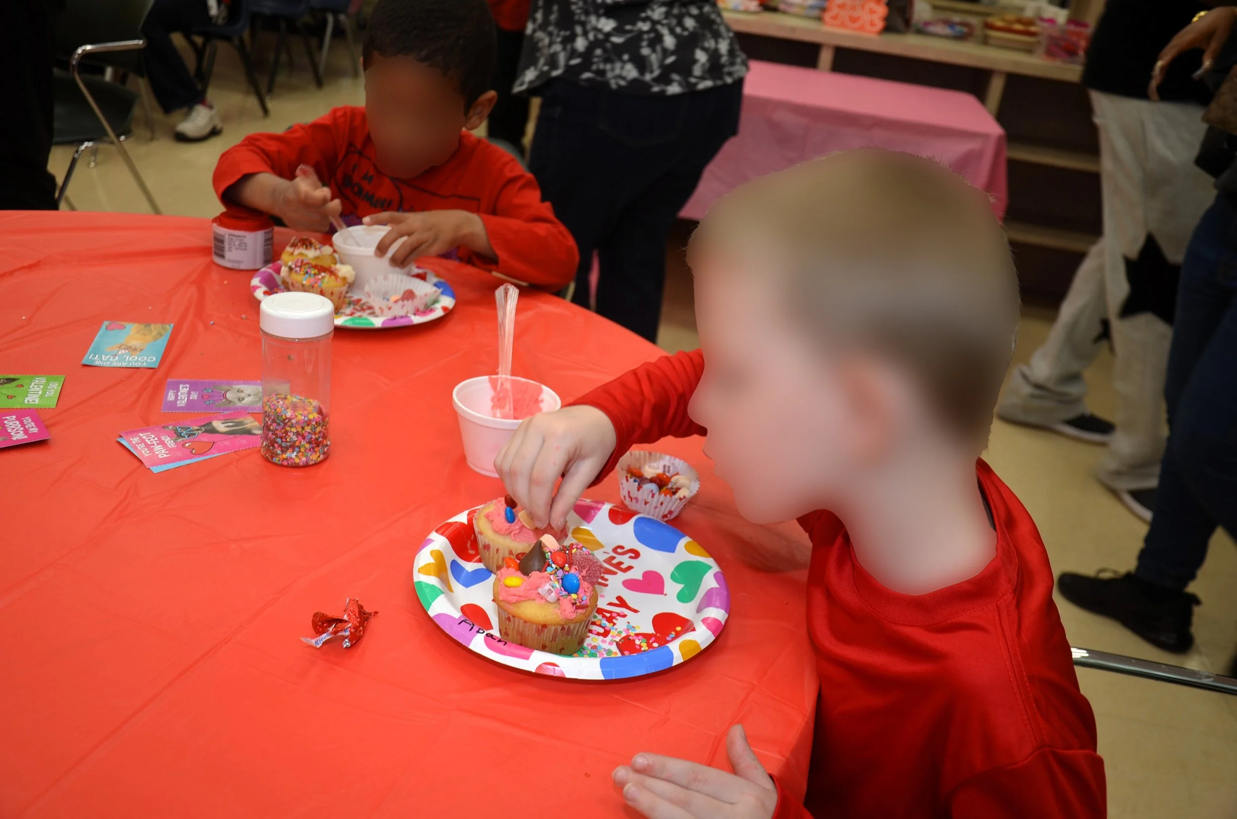 Children decorating cupcakes at a party table.