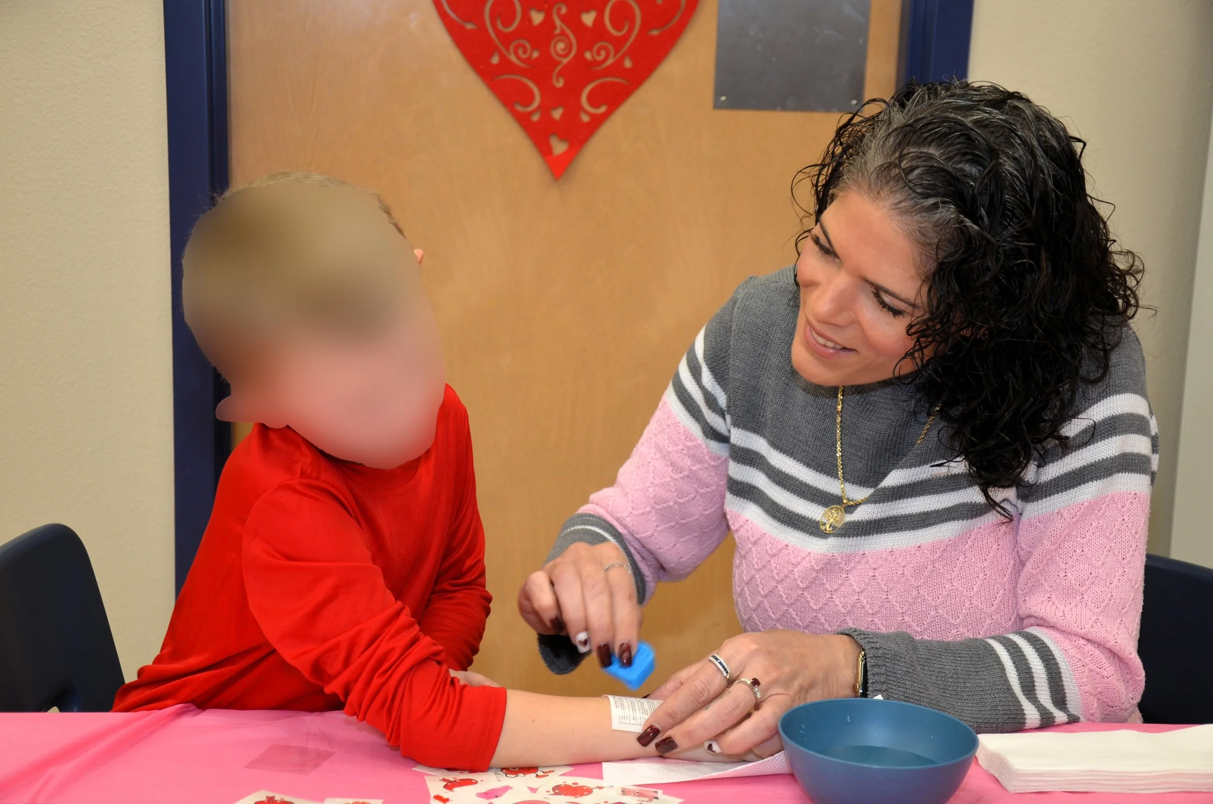 Adult assisting child with craft activity.