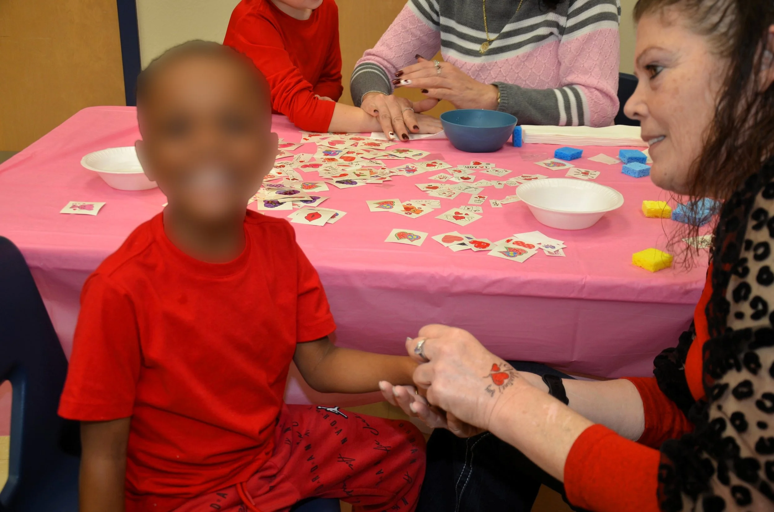 Child receiving temporary tattoo at activity table.