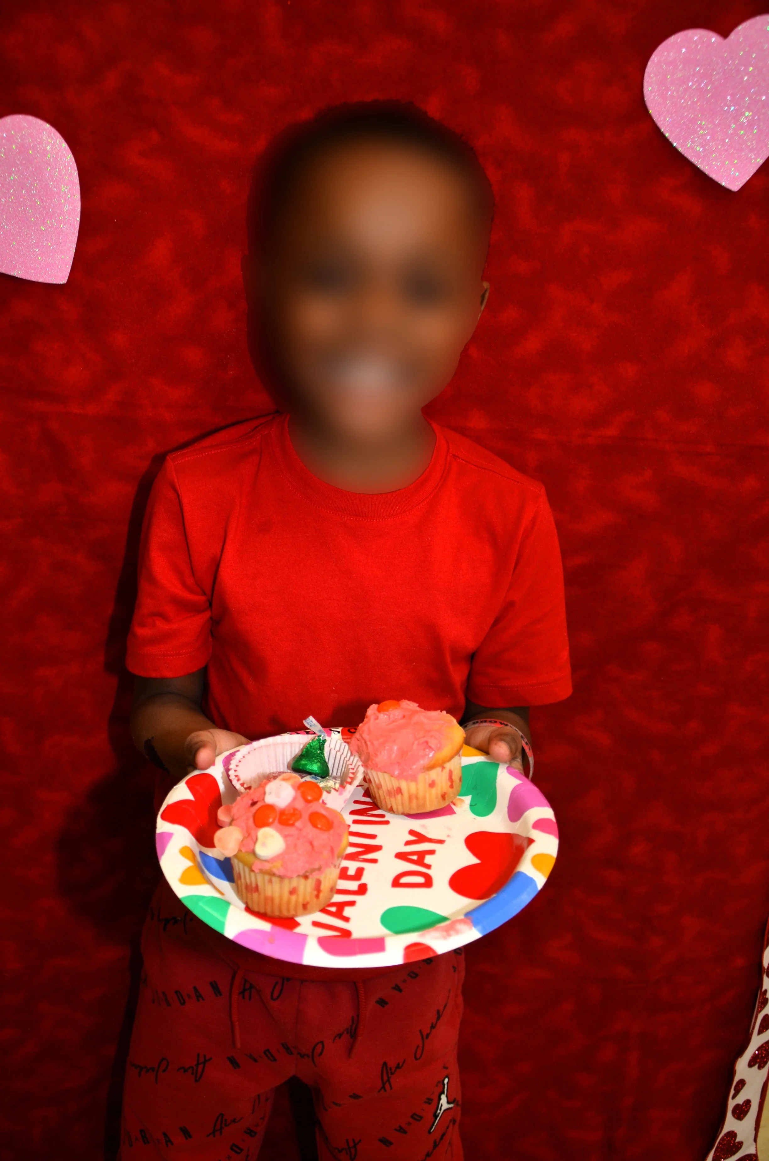 Child holding Valentine-themed cupcake plate.