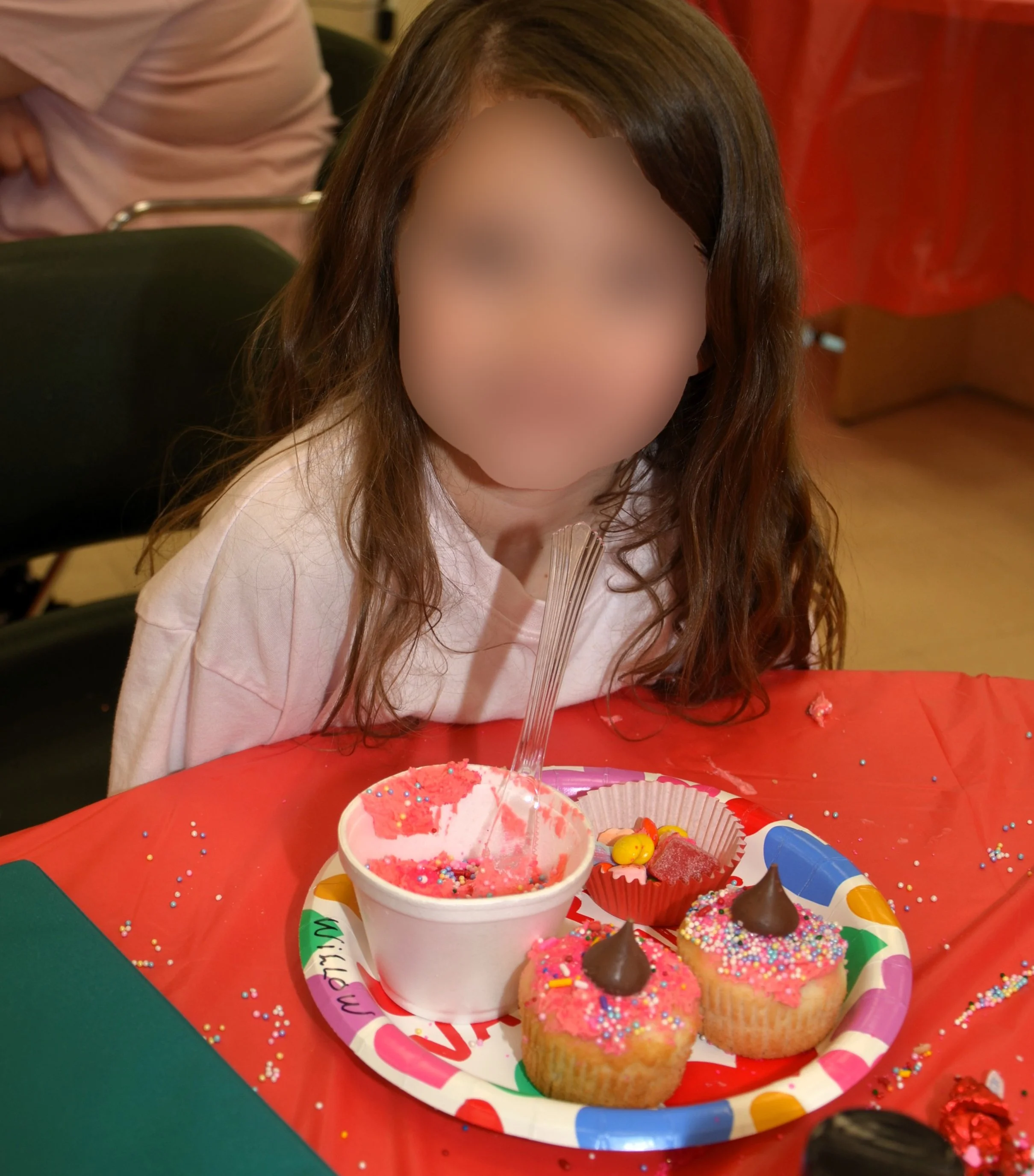 Child enjoying decorated cupcakes at table.