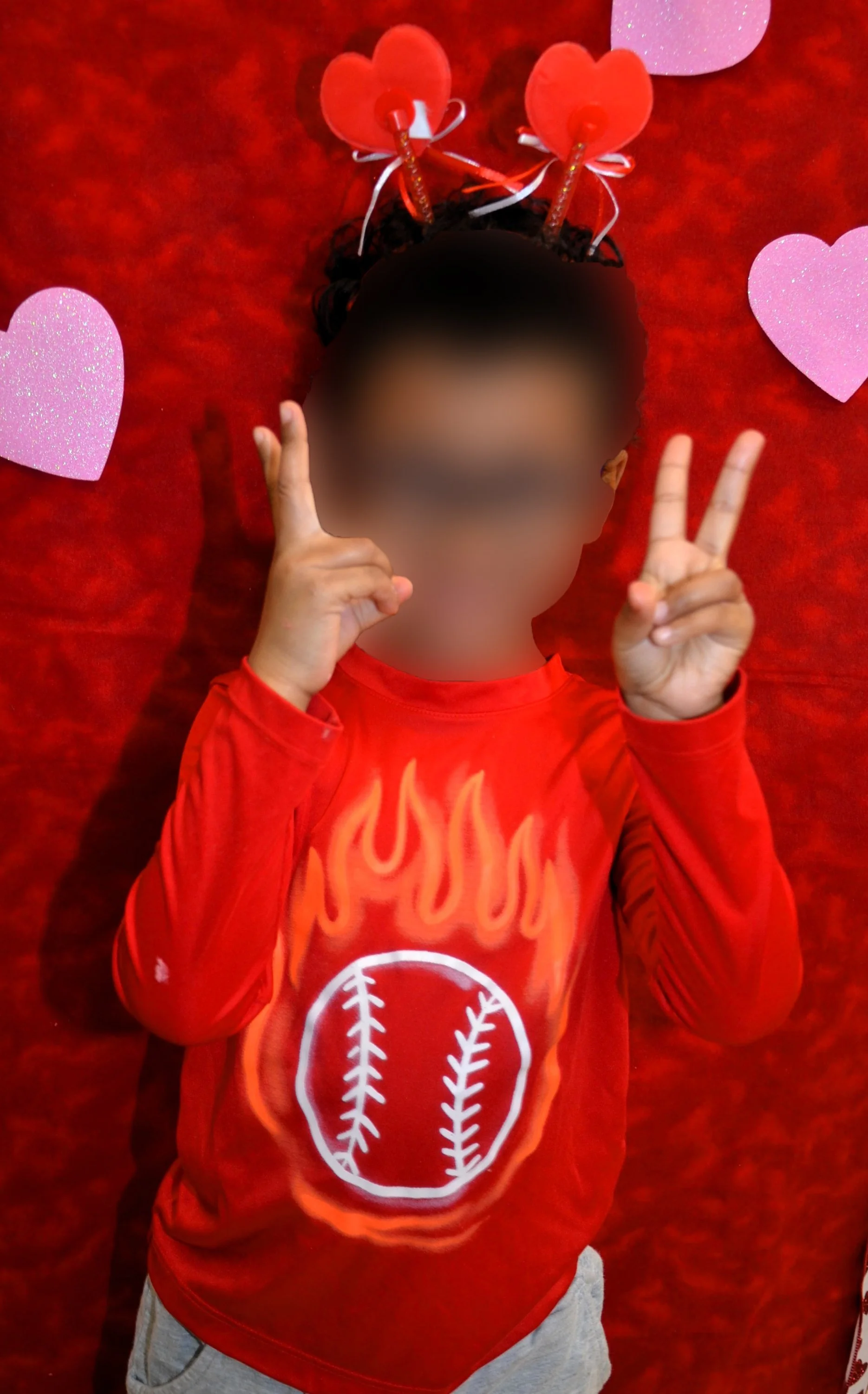 Child in red shirt with heart accessories.