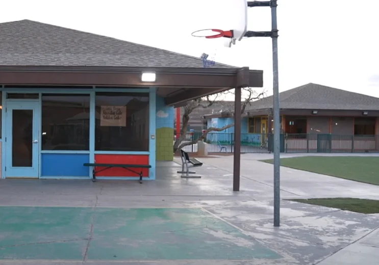 Schoolyard with basketball hoop and building.